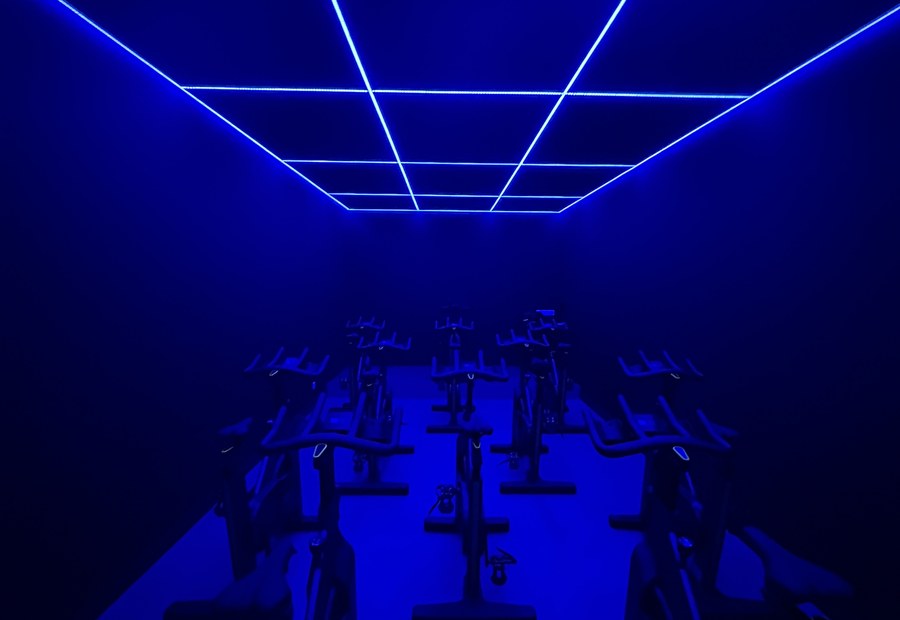 Salle de sport — studio biking lumière LED bleue aménagé par Ovrance